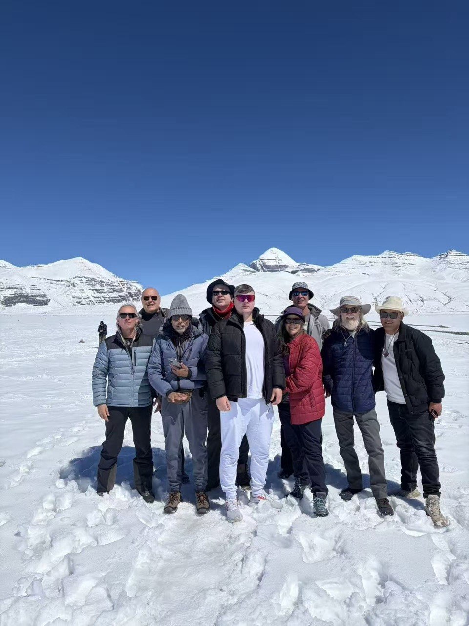 Group standing in deep snow with mountain backdrop